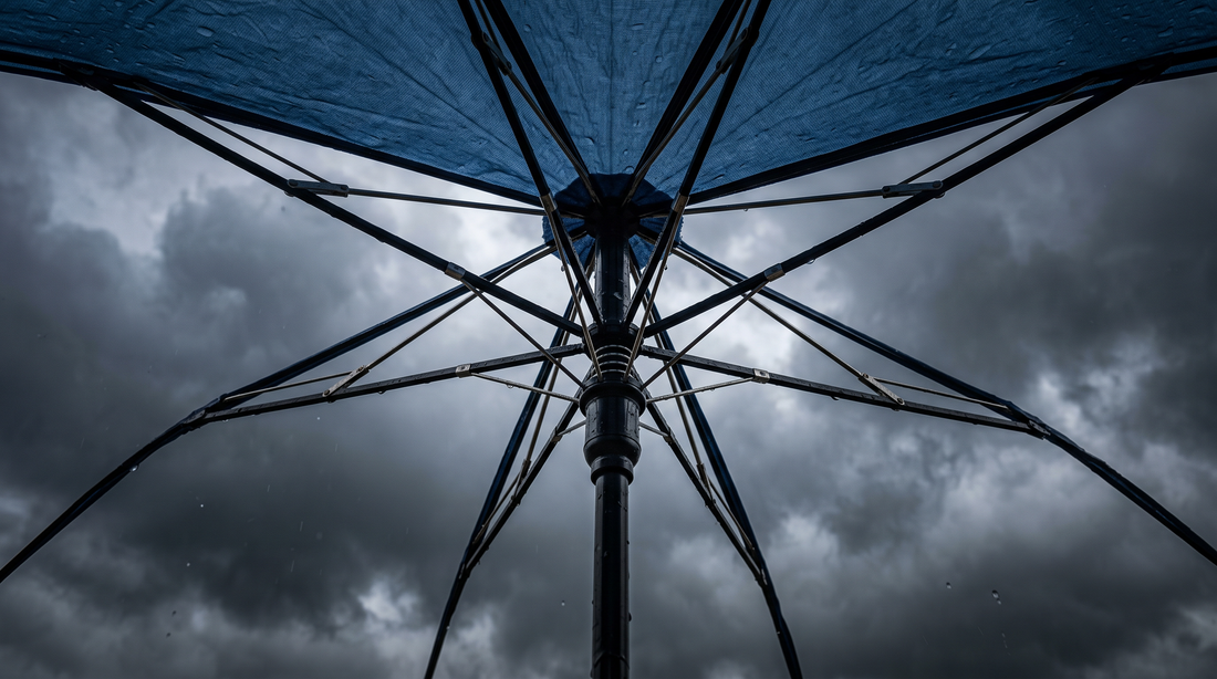 Close-up of umbrella ribs flexing against strong wind and rain on a monsoon street, illustrating the stress an umbrella frame endures