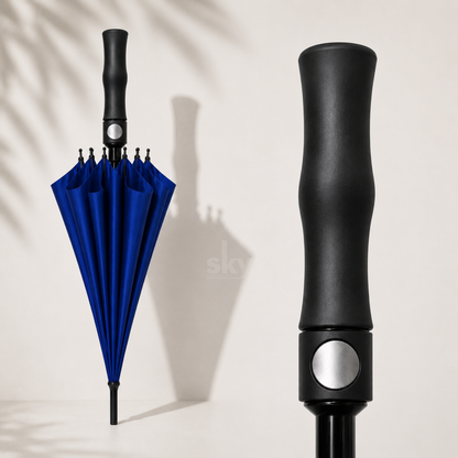 A blue folding umbrella shown open on the left and a close-up of its black handle on the right, set against a warm off-white background with soft leaf shadows.