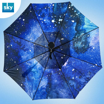 An open umbrella viewed from above, featuring a blue and black galaxy space print with white stars, set against a light blue gradient background. 