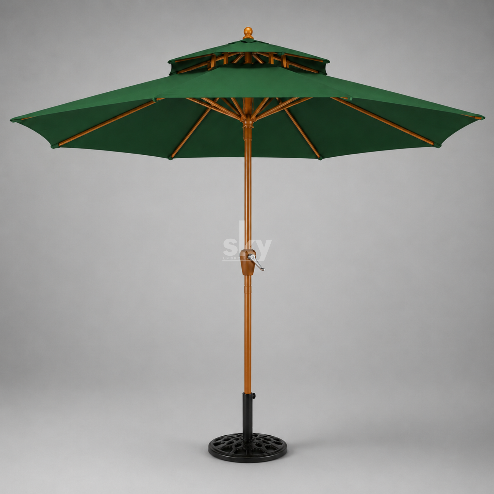 A green patio umbrella with a wooden pole finish and black metal base, shown against a neutral gray background.