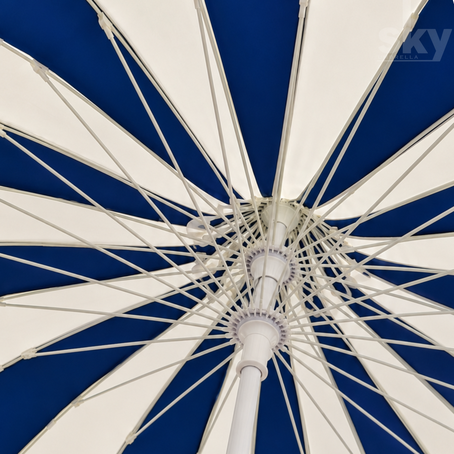 Close-up interior view of a large patio umbrella canopy with alternating white and deep blue panels and a white premium quality central hub and ribs.