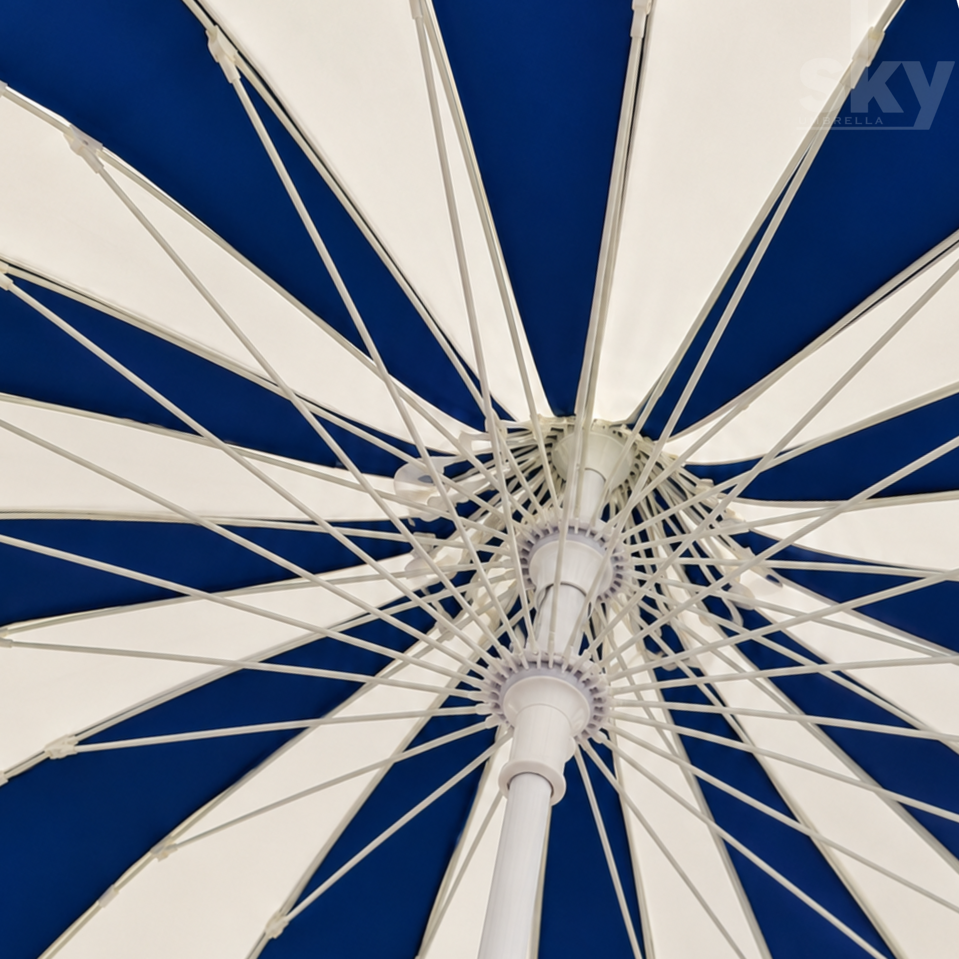 Close-up interior view of a large patio umbrella canopy with alternating white and deep blue panels and a white premium quality central hub and ribs.