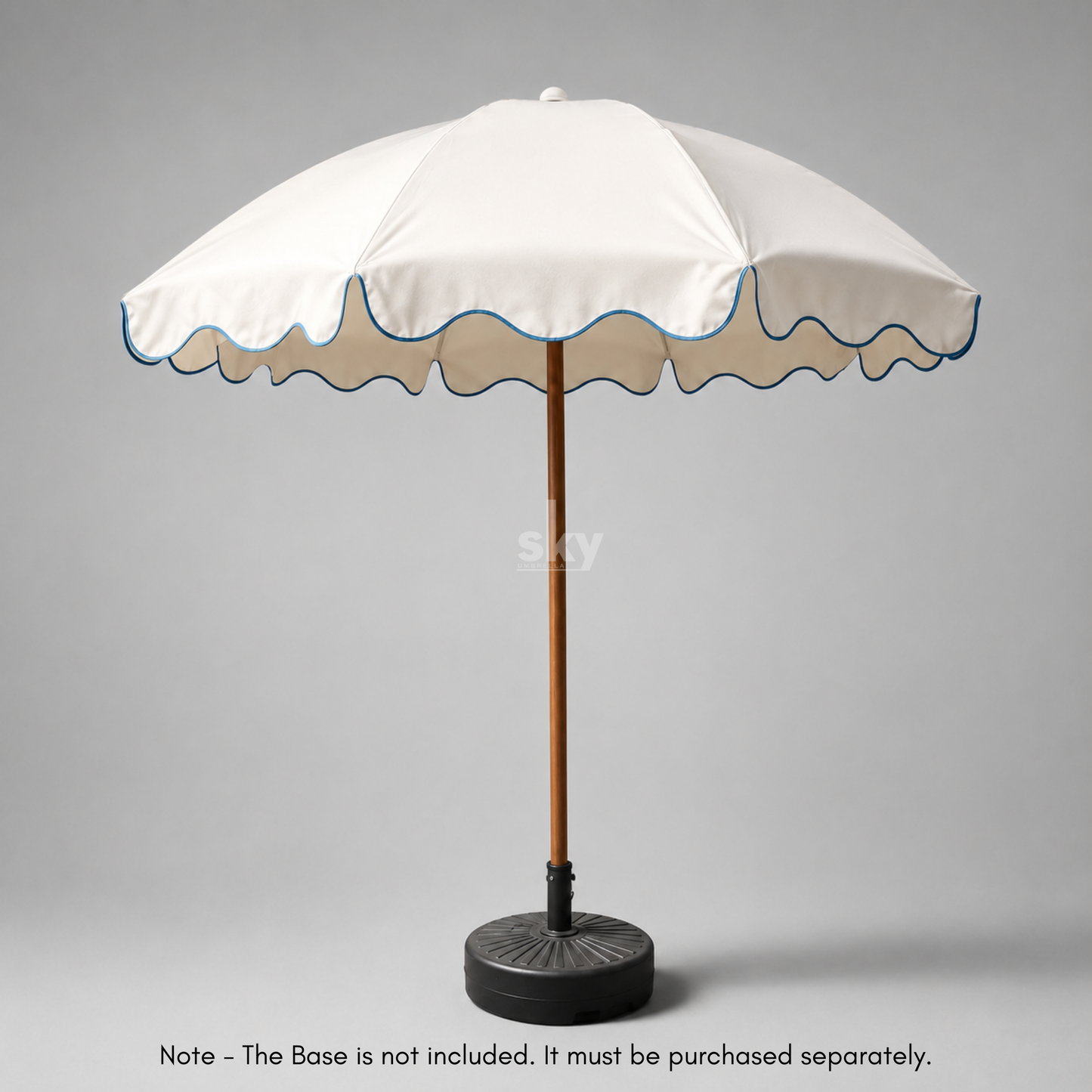 A white patio umbrella with a scalloped edge, blue piping, a brown pole, and a black weighted base on a white background.