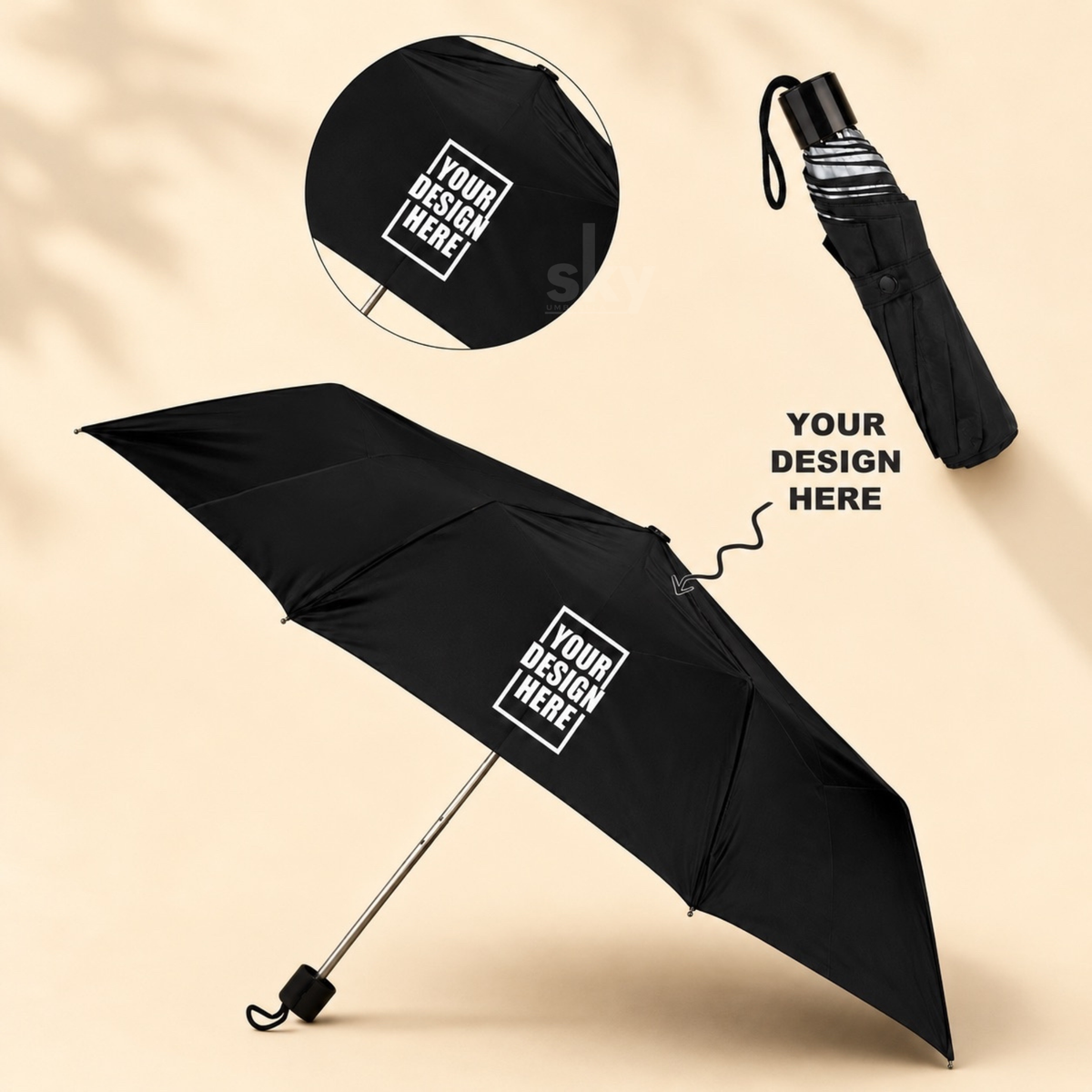 A customizable black folding umbrella shown open and closed on a warm beige background, with mockup text reading 'YOUR DESIGN HERE' and a circular inset showing the canopy print area.
