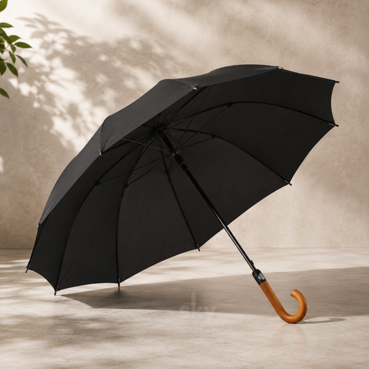 A black open umbrella with a curved light brown wooden handle, photographed on a beige floor against a textured beige wall. With custom brand logo printing available.