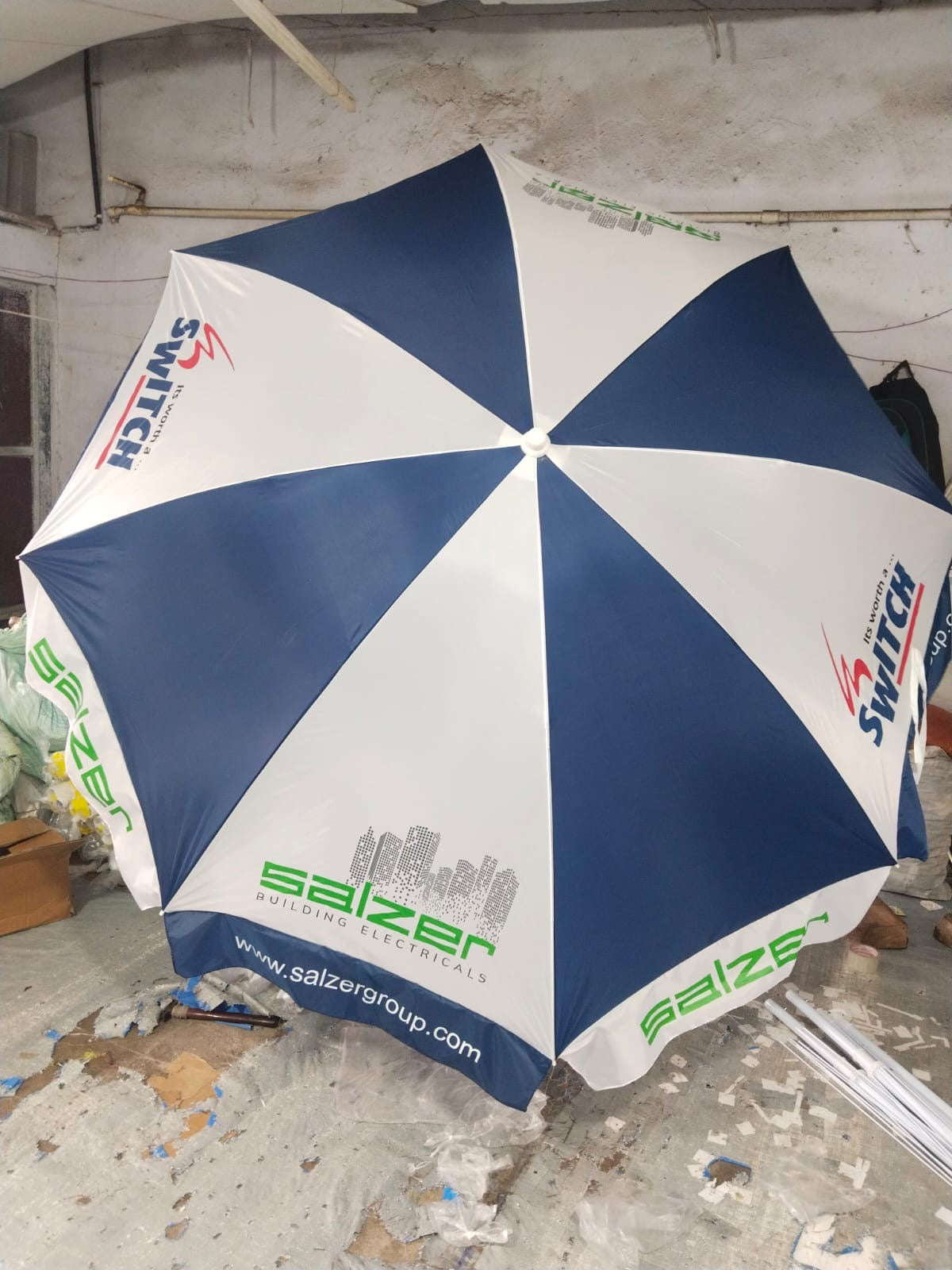 Blue and white Promotional umbrella with branding on a concrete floor