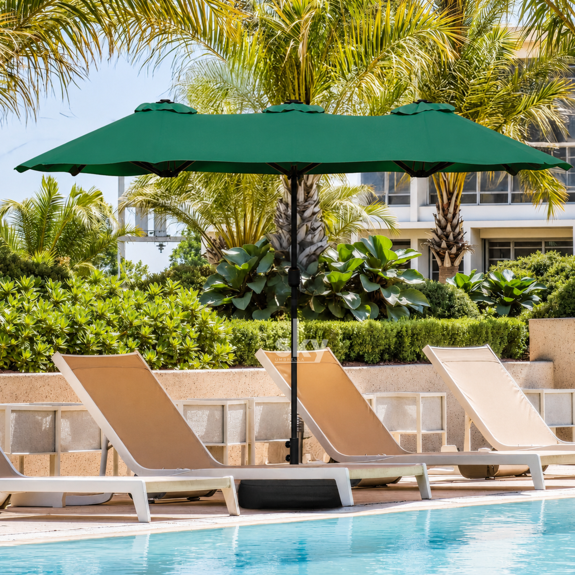 A green patio umbrella with a rectangular shade stands over three beige lounge chairs beside a swimming pool, with palm trees and a resort-style building in the background.