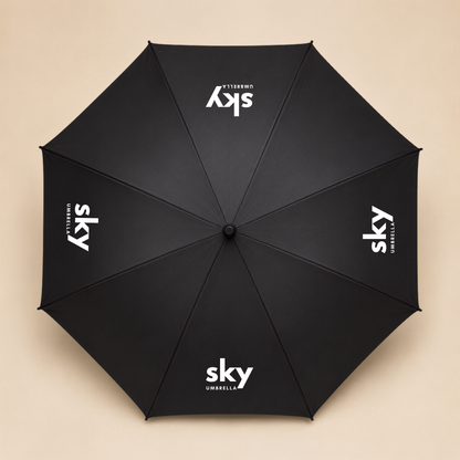 A black umbrella shown from above, with the white 'sky umbrellas' logo printed on alternative panel, set against a solid beige background.